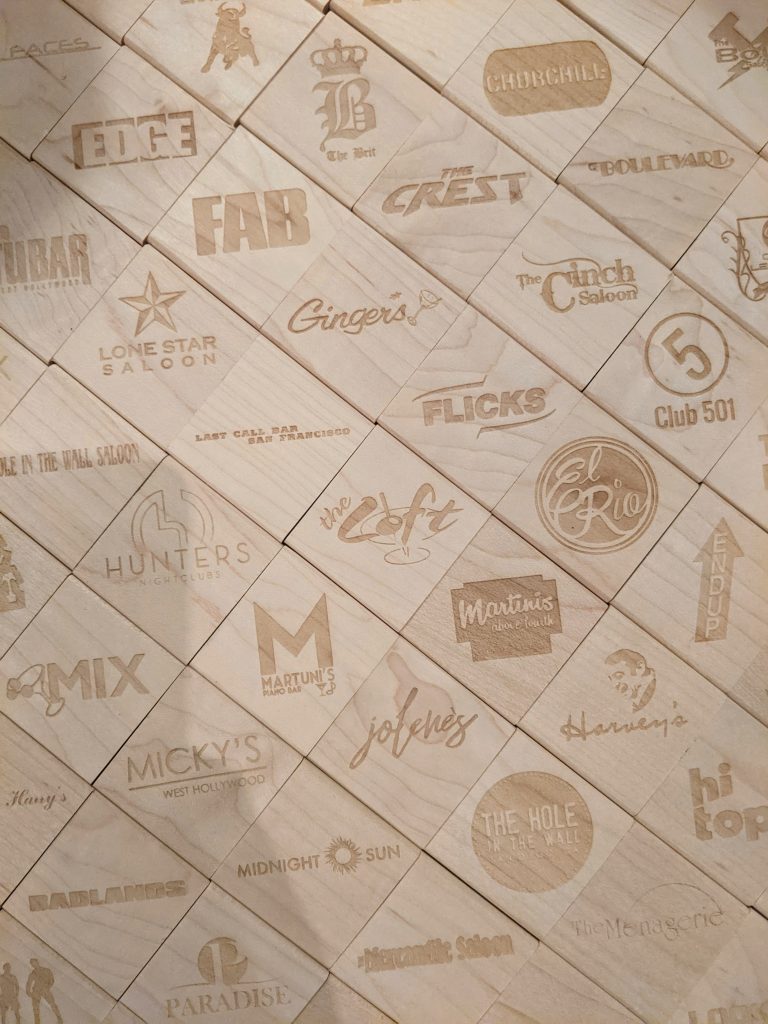 close up of a set of wooden stamps with the logos of gay bars laser cut into them